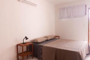 um quarto com uma cama e um candeeiro sobre uma mesa em Casa do Pepe em Cairu