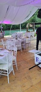 a group of white tables and chairs under a tent at Villa California in Rezine