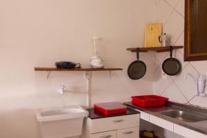 uma cozinha com um lavatório e um balcão com panelas e frigideiras em Casa do Pepe em Cairu