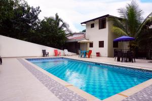 a swimming pool with tables and chairs and a house at FINCA EL PROGRESO cabañas tipo apartamento in Anapoima