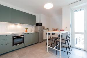 una cucina con armadi verdi e un tavolo con sedie di Top Living Apartments - Carducci a Torino