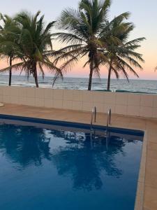 a swimming pool with palm trees on the beach at Quarto particular na praia do flamengo in Salvador