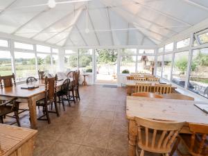 una sala da pranzo con tavoli, sedie e finestre di Far Coley Farm and Kilnhurst Log Cabin a Stafford