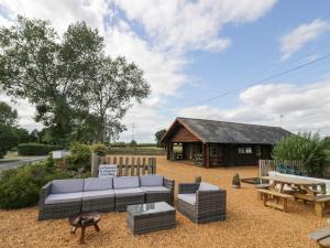 a patio with a couch and a table and a building at Far Coley Farm and Kilnhurst Log Cabin in Stafford