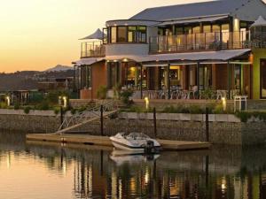 a large house with a boat in the water at Thesen View - exquisite views with bikes & canoe in Knysna