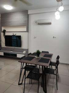 Un comedor con mesa y sillas y un televisor. en Calm and Peaceful Lake View Mount Austin Apartment, en Johor Bahru