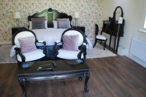 een slaapkamer met een bed met 2 stoelen en een tafel bij Clonganny House in Ballygarrett