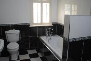 een zwart-witte badkamer met een toilet en een bad bij Clonganny House in Ballygarrett