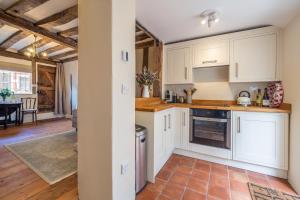 a kitchen with white cabinets and a dining room at Angelic 16th Century cottage in key Constable village - Bear Cottage in Nayland