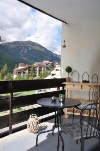 Un patio con una mesa y sillas en un balcón. en Serre Chevalier, Superbe appartement 5/7 couchages, en Saint-Chaffrey