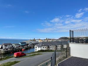 a red car parked on a street next to a harbor at The New 2 Plas Morolwg in Aberystwyth