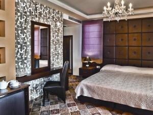 a bedroom with a bed and a chair and a mirror at Phaidon Hotel & Spa in Florina