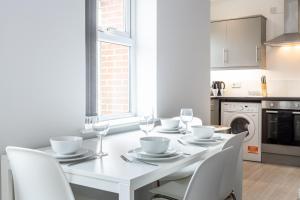 a white dining room with a white table and chairs at Pillo Rooms Serviced Apartments - Trafford in Manchester