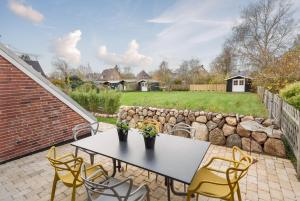 un patio con mesa, sillas y pared de roca en Lieblingshome, en Tinnum