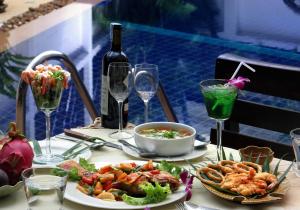 a table with a plate of food and a bottle of wine at Karon Pool Hotel in Karon Beach