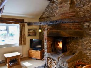 a living room with a stone fireplace and a television at Blacksmiths Cottage in Gillamoor