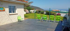 a group of green chairs sitting on a patio at CASA EN PLAYA DE RAZO CON JARDIN Y VISTAS AL MAR in Razo
