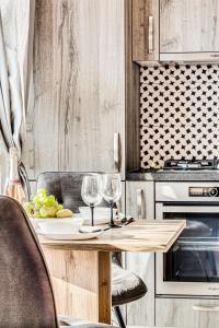 eine Küche mit einem Holztisch mit zwei Weingläsern in der Unterkunft ARI Brownie Apartment near AFI Mall in Arad