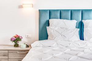 a bed with white sheets and a blue headboard at ARI Brownie Apartment in Arad