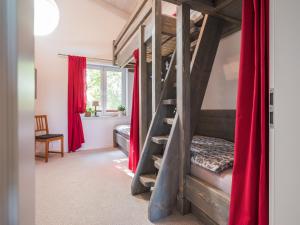 a bedroom with a bunk bed with red curtains at Waldsiedlung No2 in Kröpelin