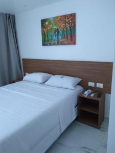 um quarto com uma cama branca e uma mesa de cabeceira com uma fotografia em Pousada Sky Beach Flat em Porto de Galinhas