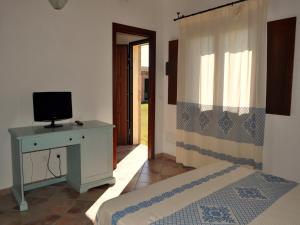 een slaapkamer met een bed en een bureau met een televisie bij B&B Pubulos in Olbia