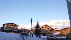 a ski lodge with snow covered mountains in the background at Studio des Jeux - Alpe d'Huez Hyper Centre - 4-5 personnes - Wifi in LʼHuez