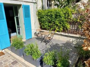 a patio with two chairs in front of a building with blue doors at STUDIO HYPER CENTRE SAINT GERMAIN EN LAYE in Saint-Germain-en-Laye