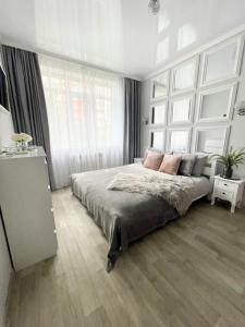 - une chambre avec un grand lit et de grandes fenêtres dans l'établissement Apartment Studio PARIS 92, à Irpin