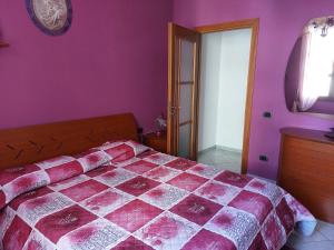 a bedroom with a bed and a purple wall at Bilocale La Genuina in Guspini