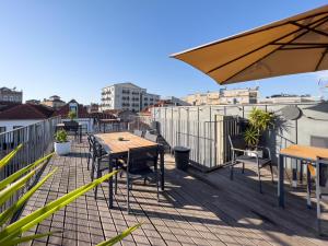 una terraza con mesas, sillas y sombrilla en Galerias Nightlife Fashion Flats, en Oporto