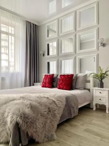 Apartment Studio PARIS 92 في إيربين: غرفة نوم بيضاء مع سرير كبير مع وسائد حمراء