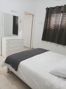 a bedroom with a bed and a dresser and a mirror at נוגה בגולן in Qasrîne