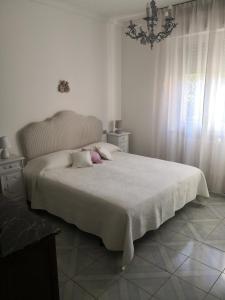 a white bedroom with a large bed with pink pillows at Le stanze di Angelina in Foligno