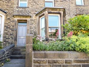 a brick house with a blue door and some flowers at Number 61 Skipton in Skipton