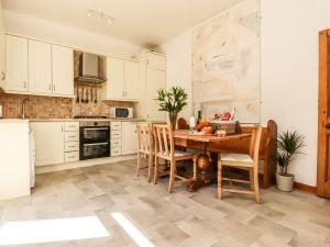 a kitchen with white cabinets and a wooden table and chairs at Number 61 Skipton in Skipton