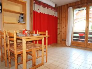 a kitchen with a table and chairs and a red curtain at Studio Morillon Village, 1 pièce, 4 personnes - FR-1-624-60 in Morillon