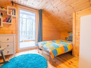 sypialnia w drewnianym domku z łóżkiem i oknem w obiekcie Czerwone Domki w mieście Domysłów