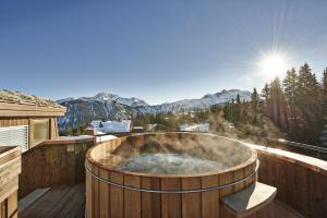 a hot tub on a deck with a view of the mountains at Apogée Courchevel, Oetker Hotels in Courchevel