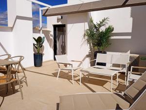 un patio con sillas blancas, mesas y plantas en LANUZA - Apartamentos Down Town Málaga Centro en Málaga