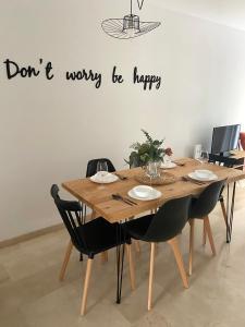 uma mesa de madeira com cadeiras e uma placa que diz: Não se preocupe, seja feliz. em Charlot Center Apartment I em Alicante