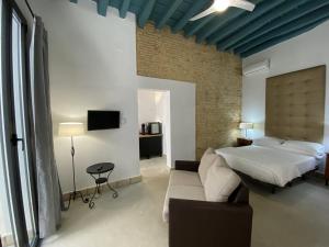 een slaapkamer met een bed en een bank bij CAMASanlúcar in Sanlúcar de Barrameda