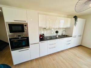 a kitchen with white cabinets and a sink and a microwave at Appartement luxueux et cosy in Cergy