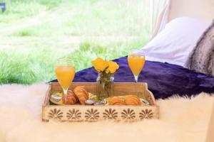 een dienblad met brood en twee glazen sinaasappelsap bij Lotus Belle Tents sleeping up to 7 Guests in Ross on Wye