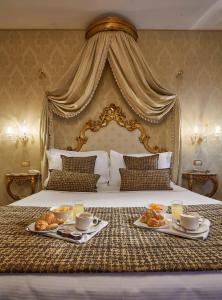 a hotel room with a bed with two plates of food on it at Hotel Orsaria in Venice