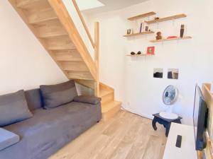 uma sala de estar com um sofá e pisos em madeira em - Le Lys - Magnifique maisonnette avec terrasse em Poitiers