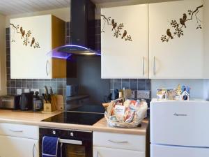 a kitchen with white cabinets and a white refrigerator at Little Gem in Kirkcaldy