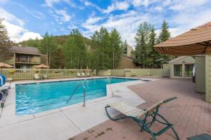 - une piscine avec une chaise et un parasol dans l'établissement Flying Dutchman by Summit County Mountain Retreats, à Keystone