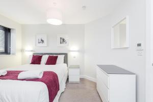 a white bedroom with two beds and a desk at Room Space Service Apartments – New Manor House in Bracknell