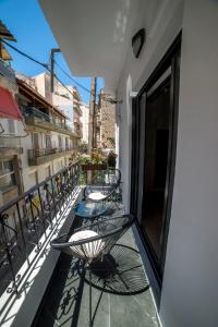 einen Balkon mit Stühlen und Tischen auf einem Gebäude in der Unterkunft Luxurious apartment in the heart of town ! in Loutraki